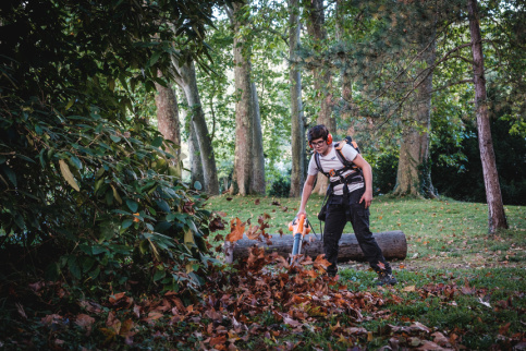 Un jeune en formation jardinier paysagiste en train de souffler les feuilles