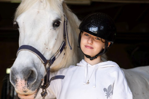 Une élève pose avec un cheval à ses côtés