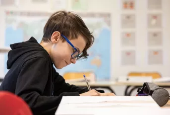 Un élève écrit sur une feuille