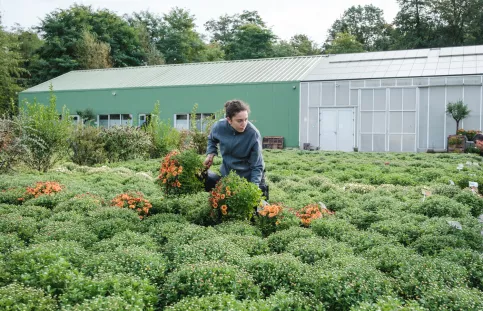 Une jeune fille s'occupant de plante devant les serres du Campus Saint-Antoine